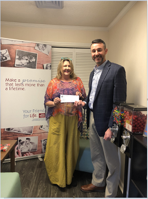 Man and woman posing with check