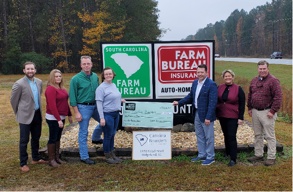 Group of people posing by highway with giant check