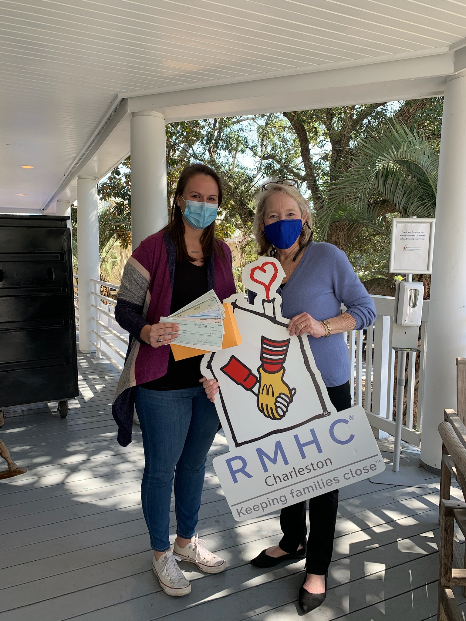 Women donors holding checks and McDonald House sign